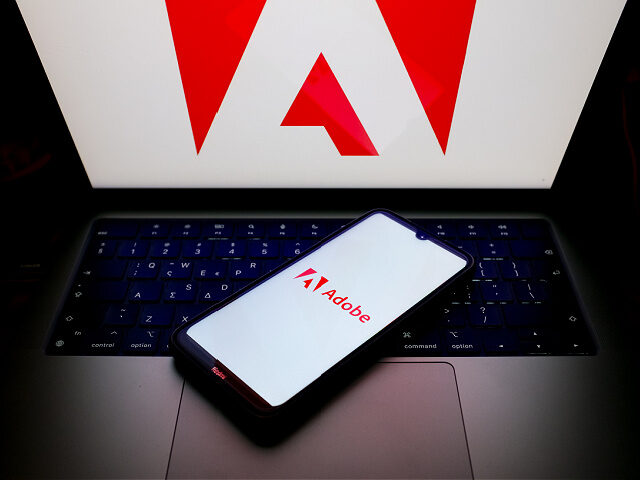 The Adobe logo is being displayed on a smartphone screen and on a computer screen in Athen