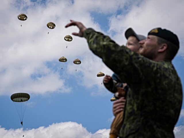 A boy and his father attend a multinational parachute drop as some 400 British, Belgian, C