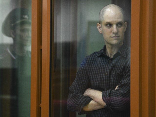 Wall Street Journal reporter Evan Gershkovich stands in a glass cage in a courtroom in Yek