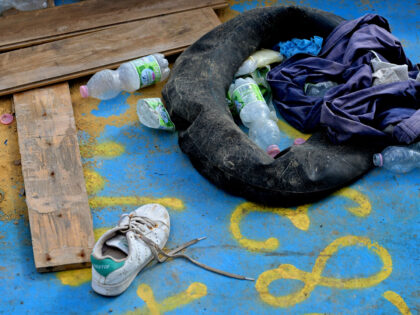 Clothes and a tube used as a buoy are abandoned in a wooden boat used by migrants to cross