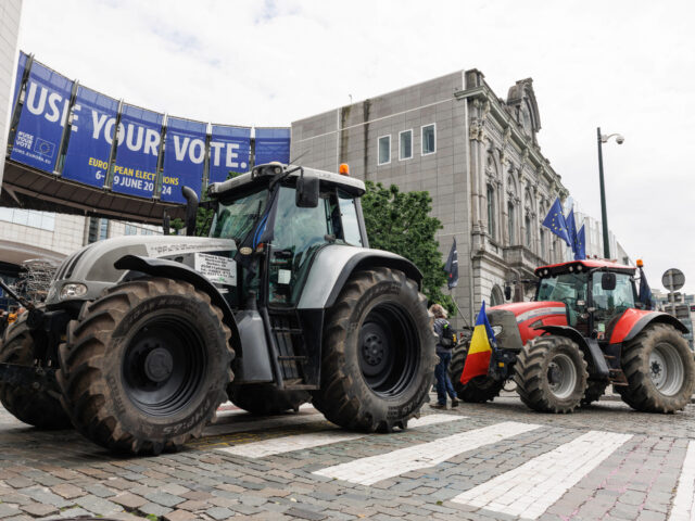 This photograph shows parked tractors in front of a giant poster announcing the upcoming E