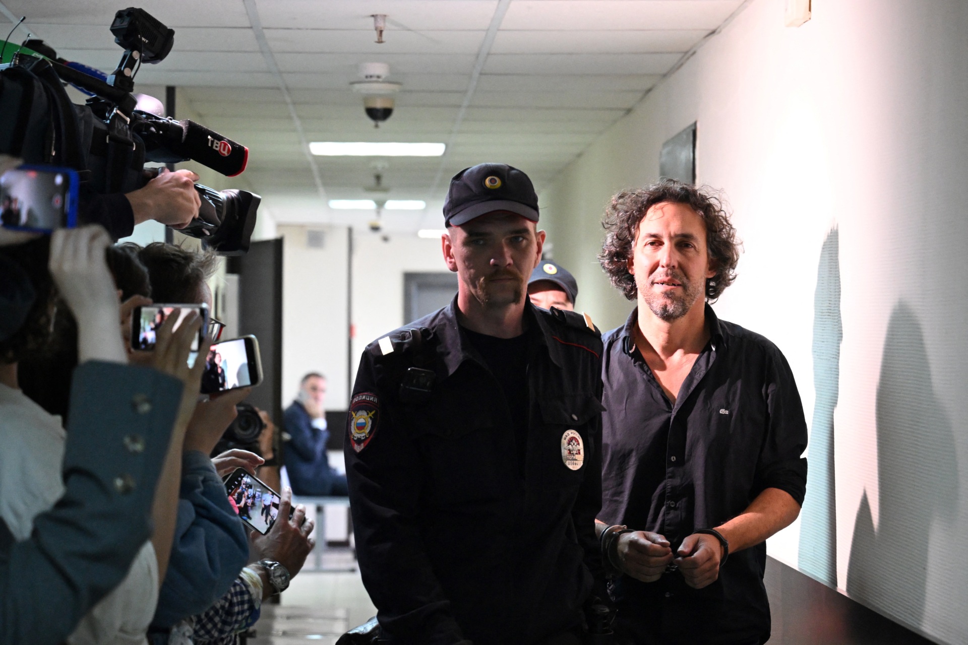 Laurent Vinatier (R), a French national who works with a Swiss-based conflict mediation non-profit organisation, is escorted by a Russian law enforcement officer prior to his pre-trial detention hearing in Moscow on June 7, 2024.