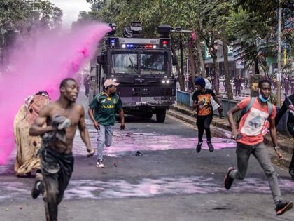 Protesters run to take cover as a Kenya Police water cannon truck throws water to them whi