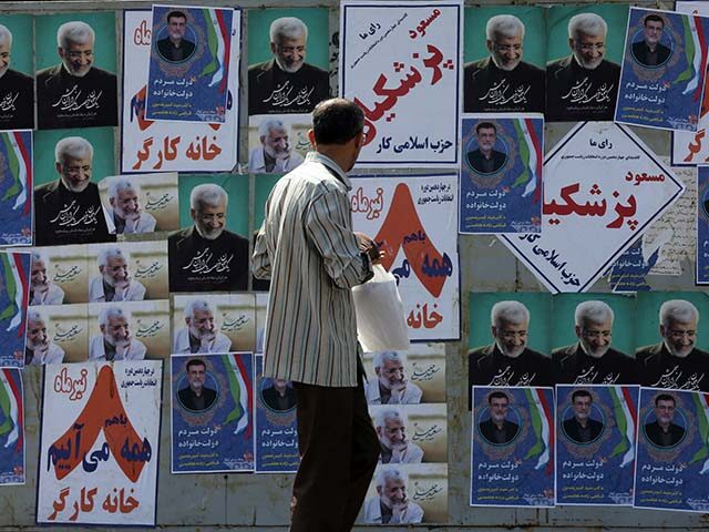 A citizen is seen in front of the candidates posters for the 14th presidential elections o