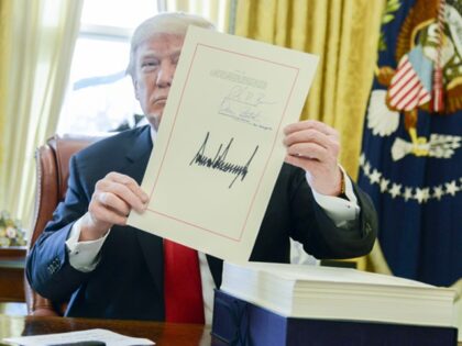 U.S. President Donald Trump holds up a tax-overhaul bill after singing it into law in the
