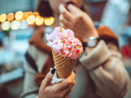 Teen girl with pink eating ice-cream outdoors in summer - stock photo