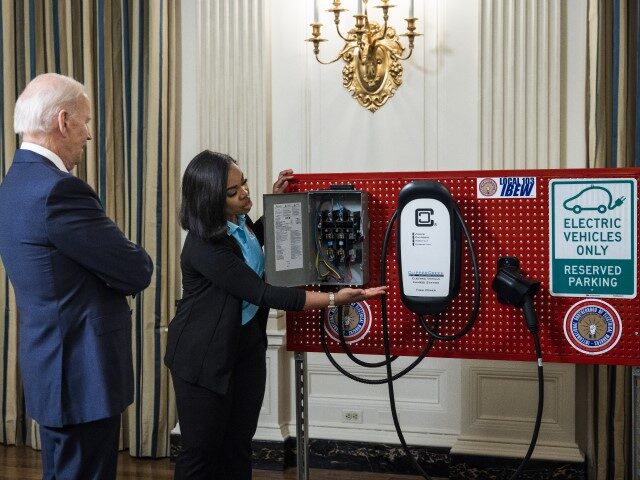 US President Joe Biden, left, views an electric vehicle charger during workforce training