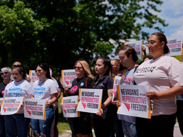 People hold signs during a news conference by Nevadans for Reproductive Freedom, Monday, M