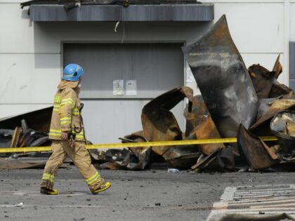 A firefighter walks near the debris at the site of a burnt battery manufacturing factory i