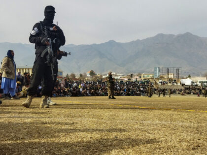 A Taliban security personnel stands guard as people attend to watch publicly flogging of w