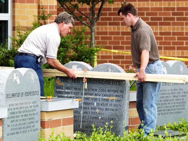 Workers remove a monument bearing the Ten Commandments outside West Union High School, Mon