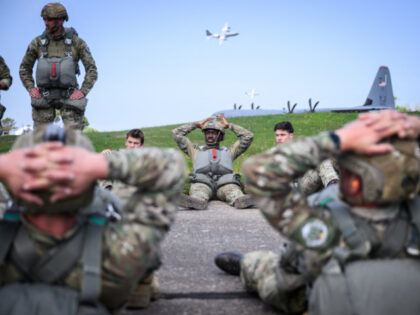 US and Belgian military Paratroopers check their parachute equipment prior to their jump f
