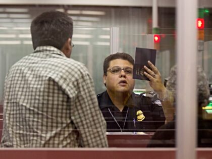 A Customs and Border Protection officer checks the passport of a non-resident visitor to t