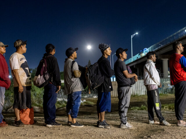 EAGLE PASS, TEXAS - SEPTEMBER 29: Under a full moon Venezuelan immigrants stand in line to