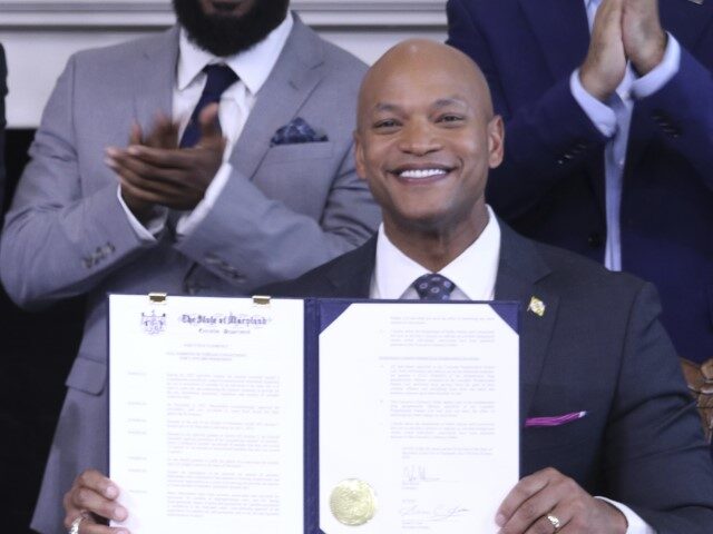 Maryland Gov. Wes Moore holds up an executive order he signed to issue more than 175,000 p
