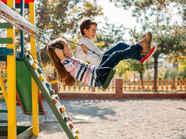 Happy children swinging in the park - stock photo