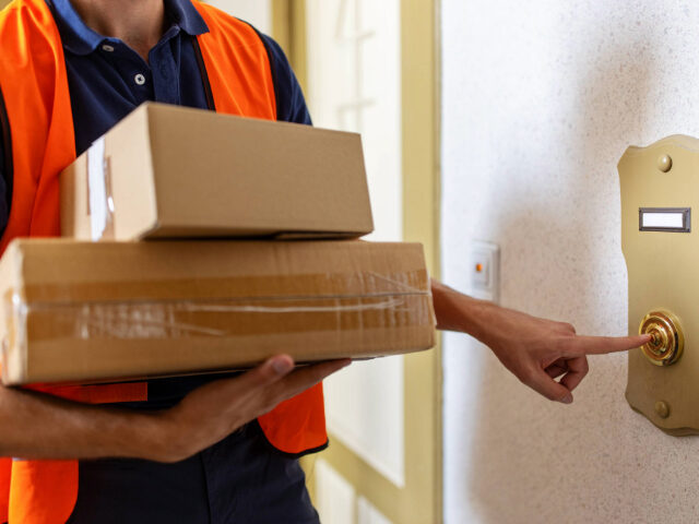 Postal worker doing a home delivery of parcel - stock photo