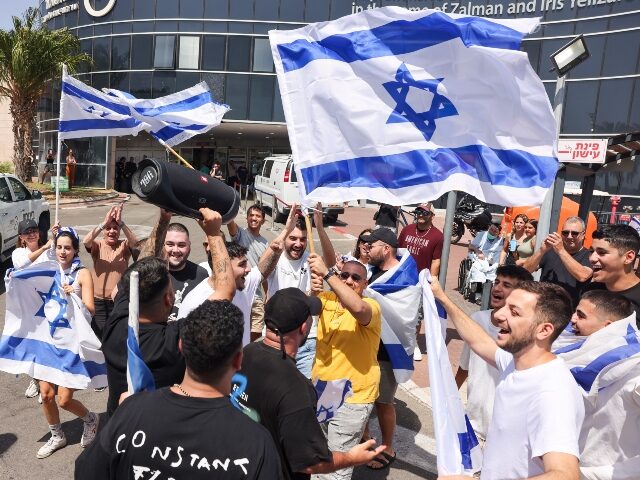 People wave Israeli flags as they celebrate after hostages who were kidnapped in a Hamas-l