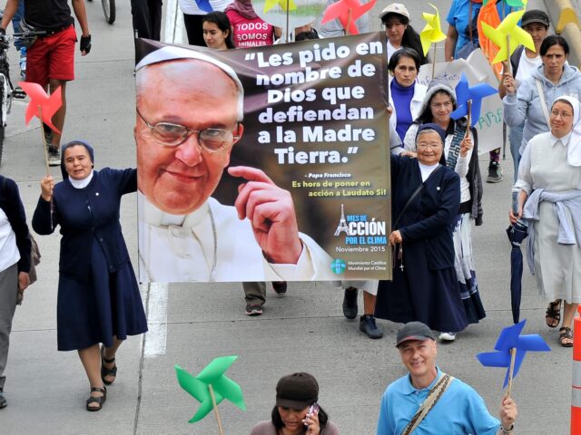 Nuns hold a banner of Pope Francis reading "I ask you in the name of God to defend Mo