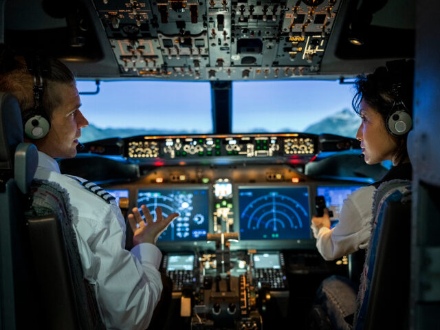 Rear view of two pilots flying an commercial airplane jet - stock photo