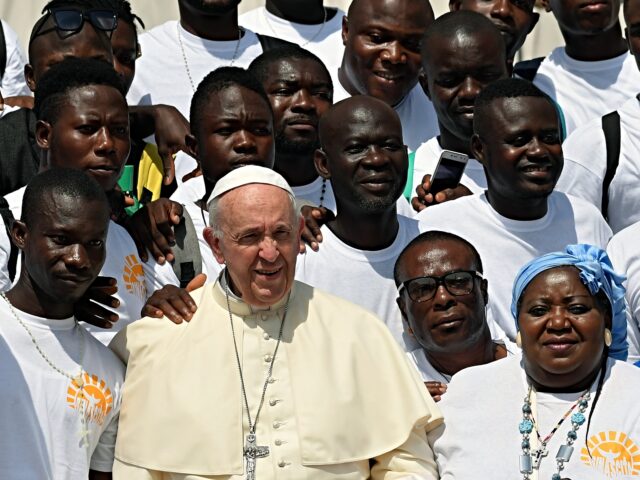 TOPSHOT - Pope Francis poses for photographs during a meeting with a group of migrants at