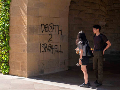 Students walk by graffiti near the office of the President at Stanford University in Palo