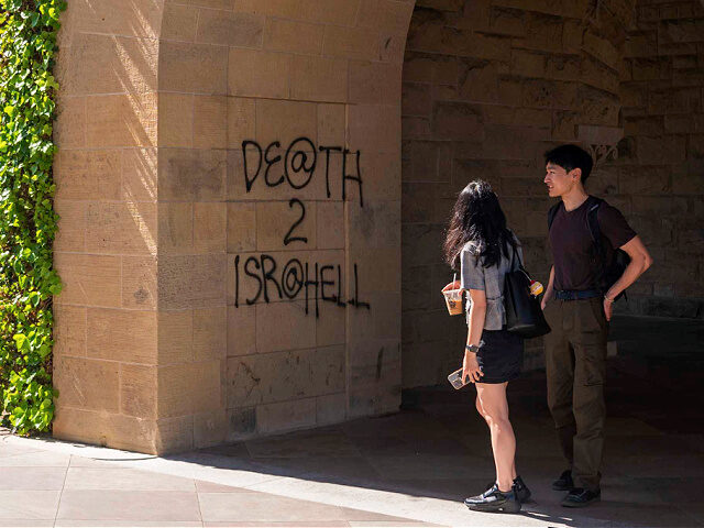 Students walk by graffiti near the office of the President at Stanford University in Palo