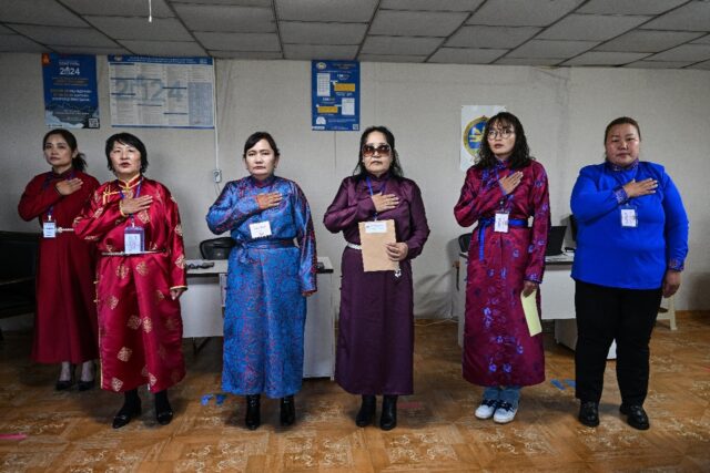 Civil servants stand for the national anthem before polls open outside Mongolia's capital