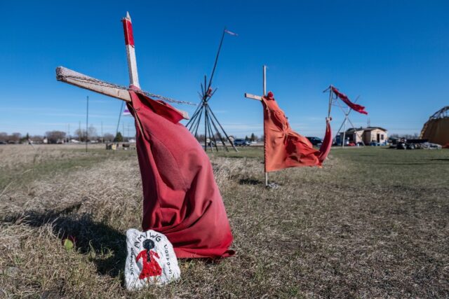 Red dresses on crosses are displayed at the entrance of a makeshift camp near near the Pra