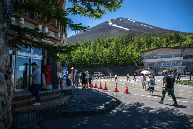 The summit of Mount Fuji is seen as people gather in front of the restaurant and shopping