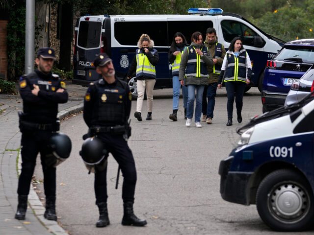 FILE - Police officers stand guard as other officers in yellow vests walk back to their ve