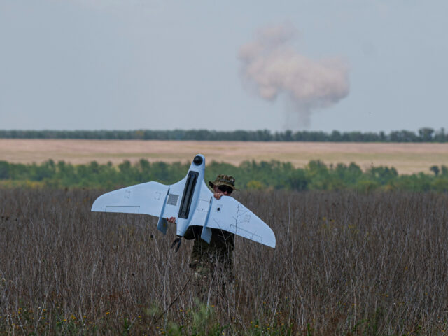 A Ukrainian serviceman of the Ochi reconnaissance unit carries a Furia drone while smoke r