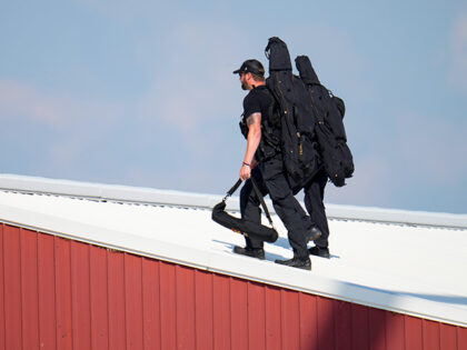 Police snipers walk on a roof to set up before Republican presidential candidate former Pr