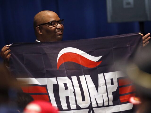 A supporter of President Donald Trump holds a Trump campaign banner as he waits for Trump