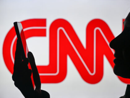 An image of a woman holding a cell phone in front of a CNN logo displayed on a computer sc
