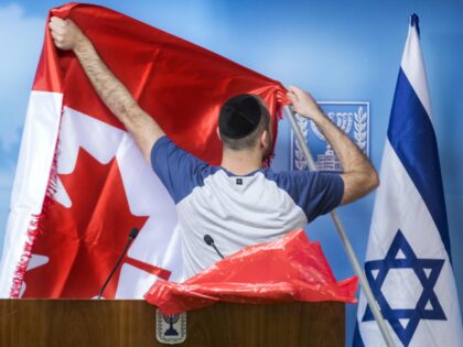 A worker prepares the Canadian flag next to the Israeli flag ahead of the arrival of Canad