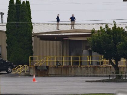 Two FBI investigators scan the roof of AGR International Inc, the building adjacent to the