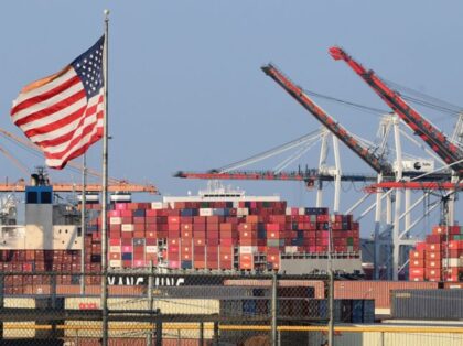 A US flag flies near containers stacked high on a cargo ship at the Port of Los Angeles o