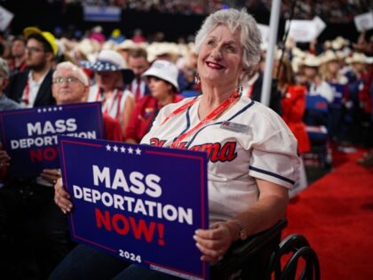 MILWAUKEE, WISCONSIN - JULY 17: A person in a wheelchair holds a sign that reads "Mass Dep