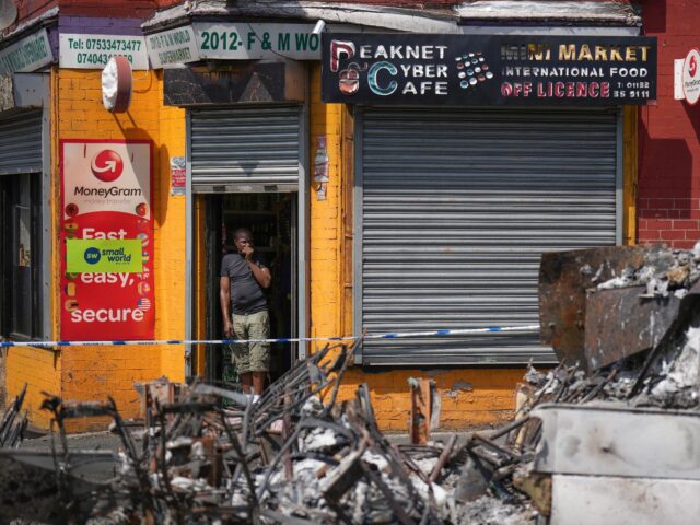 LEEDS, ENGLAND - JULY 19: Local people watch the clean up as police patrol Harehills neigh