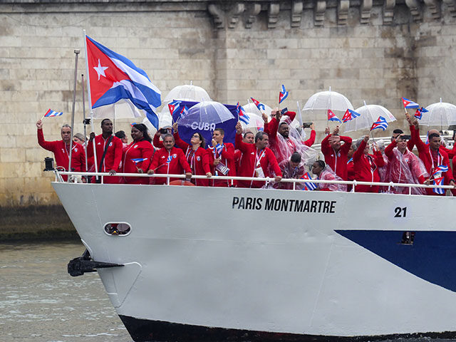 Athletes from Cuba delegation sail in a boat along the river Seine as rain starts at the s