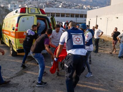 TOPSHOT - Israeli security forces and medics transport casualties along with local residen