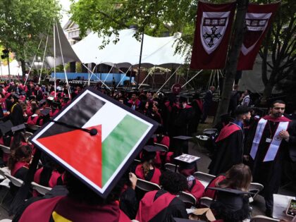 A student displays the Palestinian flag on his mortar board as graduates take their seats