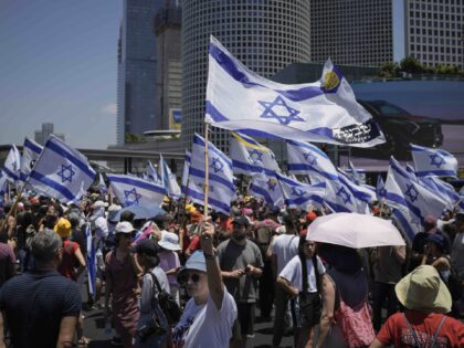 Demonstrators wave Israeli flags during a protest marking nine months since the start of t