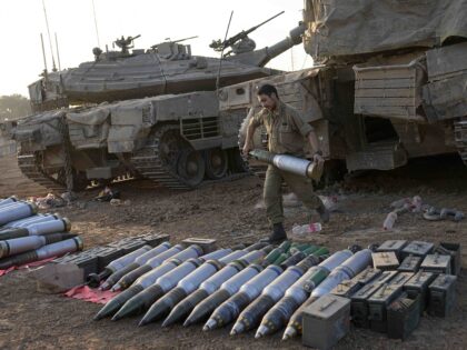 Israeli soldiers load shells onto a tank at a staging area in southern Israel near the bor