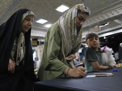 A woman fills out the ballot during the Iranian presidential election in a polling station