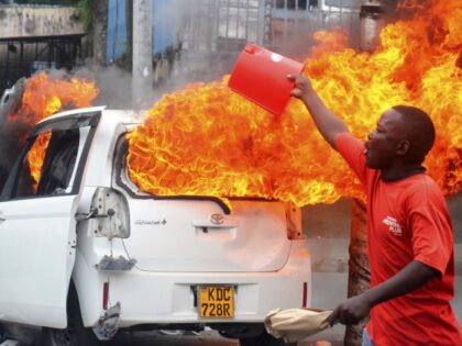 A member of the public calls for reinforcement as protesters set vehicles on fire in Momba