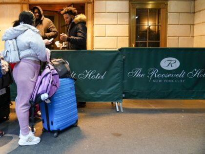 An immigrant family show their paperwork to security guards at the Roosevelt Hotel, Tuesda