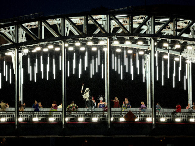 PARIS, FRANCE - JULY 26: Mysterious Torchbearer holds the Olympic Torch while on a bridge