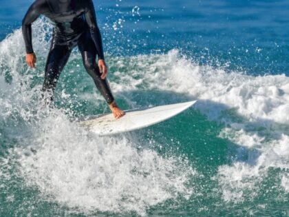 Surfer in wetsuit riding his surfboard in the pacific ocean. . ©2023 James David Phenici